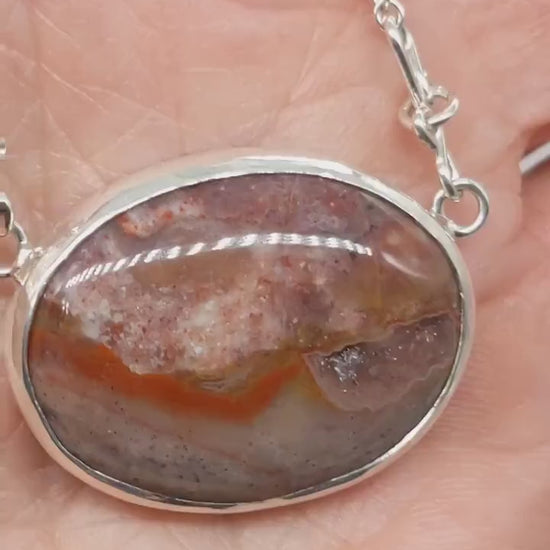 Natural Montana Jasper necklace handcrafted in Argentium 935 Silver with attached silver chain demo in hand showing features of pendant.