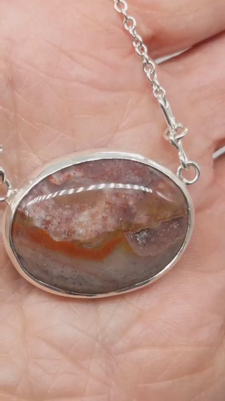 Natural Montana Jasper necklace handcrafted in Argentium 935 Silver with attached silver chain demo in hand showing features of pendant.