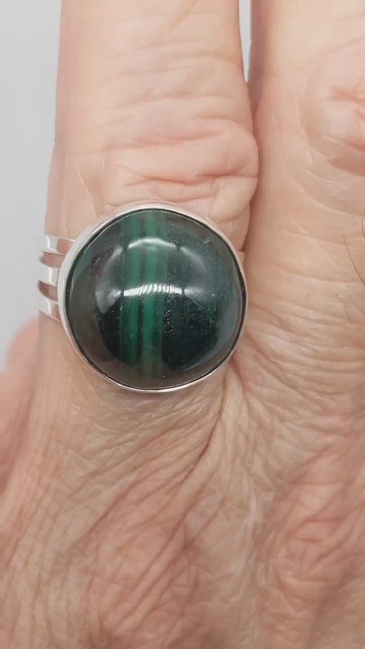 Handcrafted natural green Malachite ring with oval cabochon, polished fine silver bezel and solid Argentium 935 silver split-shank band.  Demo clip shows the ring on a hand for display.