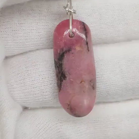 Demo clip of a Rhodonite pendant approx 1.78inches shown against a white glove background.