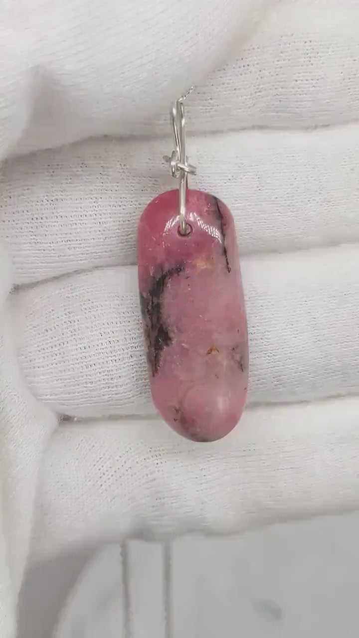 Demo clip of a Rhodonite pendant approx 1.78inches shown against a white glove background.