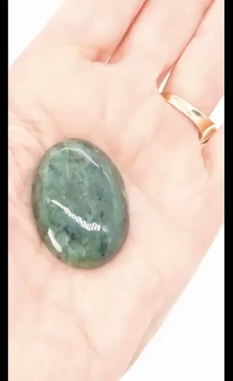 Video demonstration of a hand-cut oval Wyoming Nephrite Jade cabochon shown in the palm of a hand, highlighting its green tones, natural patterning, size and polished finish.