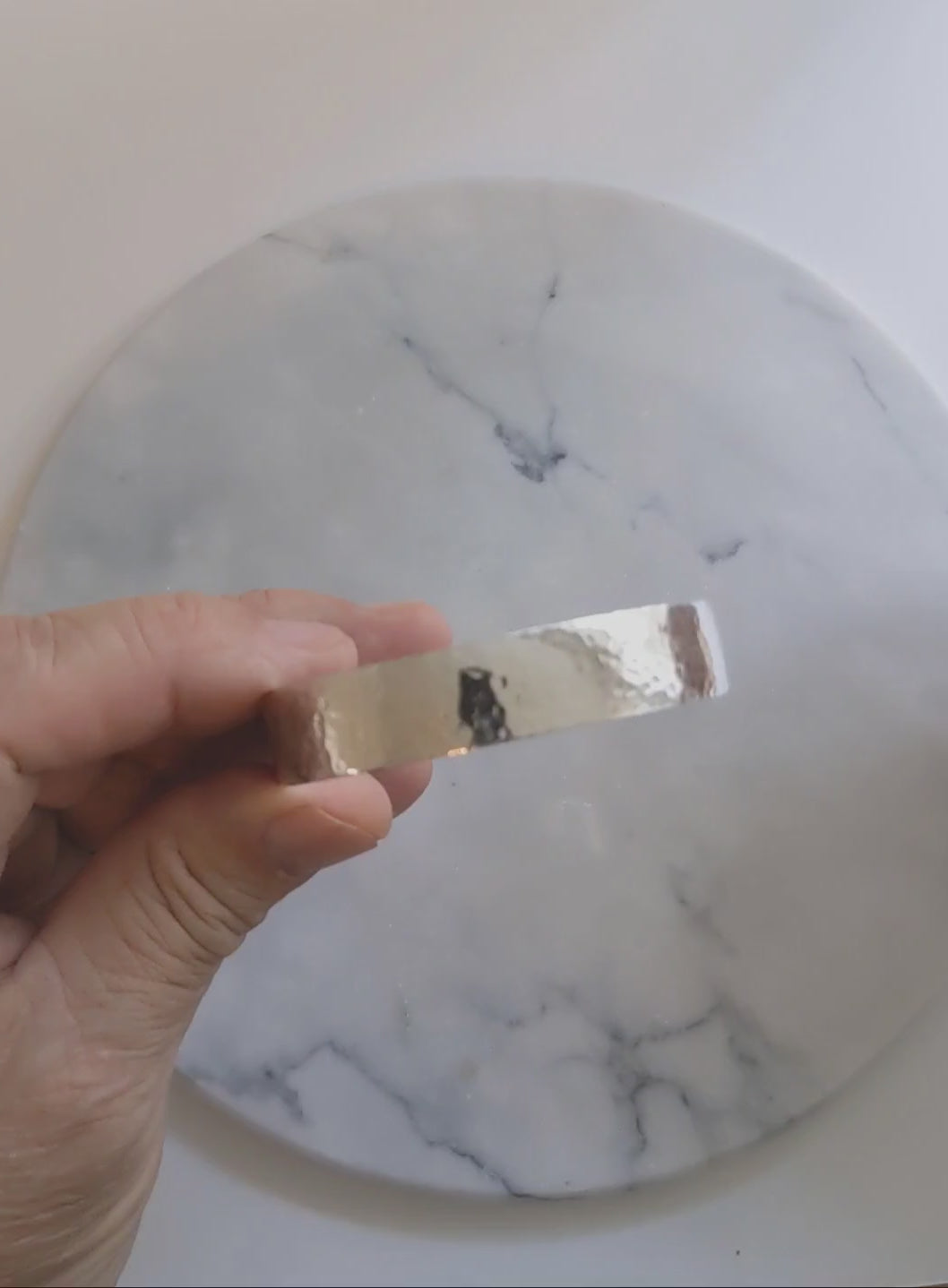 Hand-hammered sterling silver cuff bracelet with a softly curved profile, shown on a 7.5-inch wrist against a light marble-patterned background.