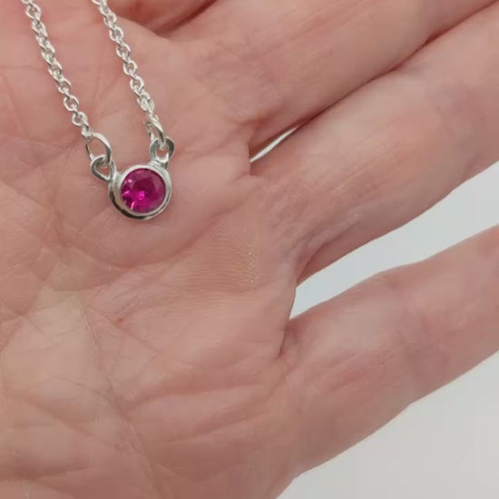 Demo Clip of Ruby Argentium Silver Pendant necklace in palm of hand with white background.