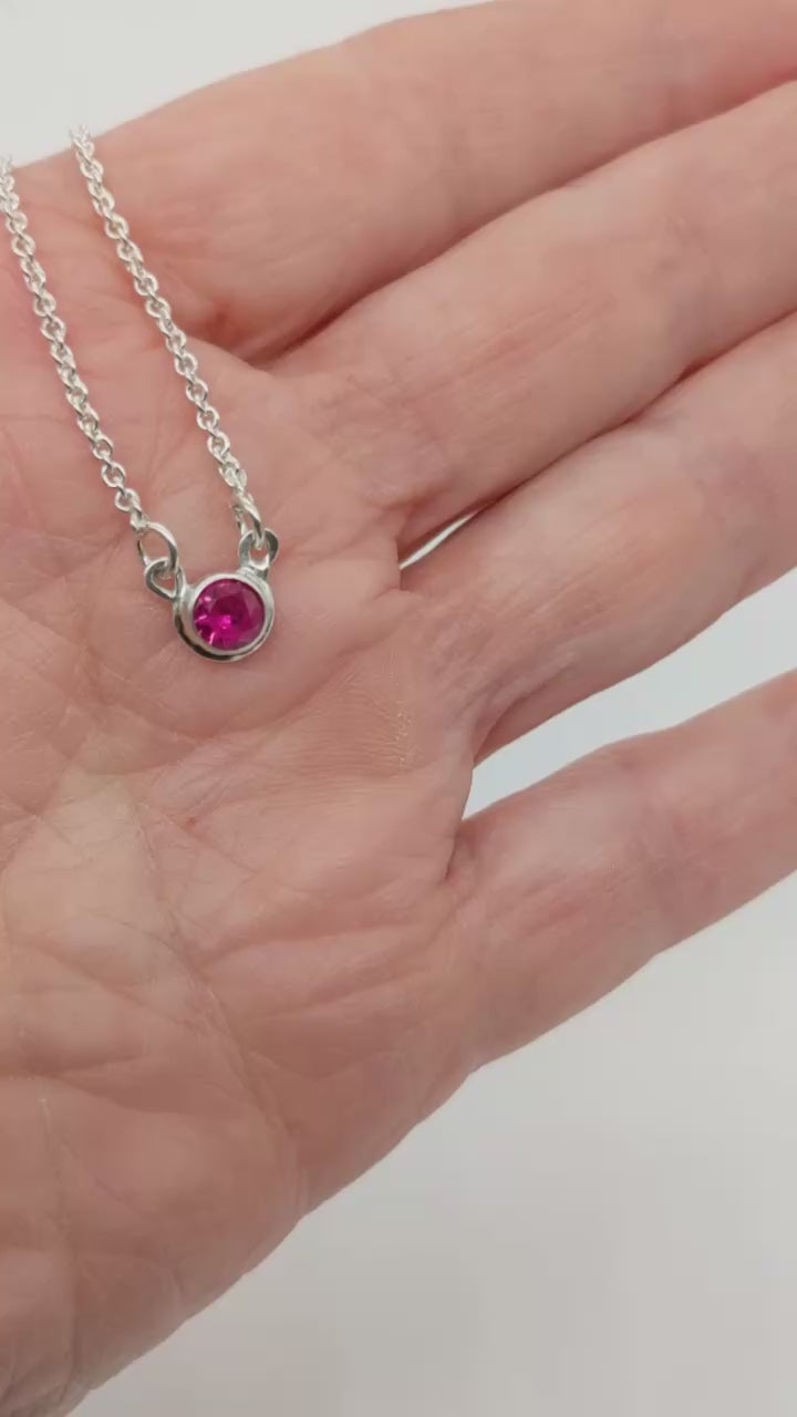 Demo Clip of Ruby Argentium Silver Pendant necklace in palm of hand with white background.
