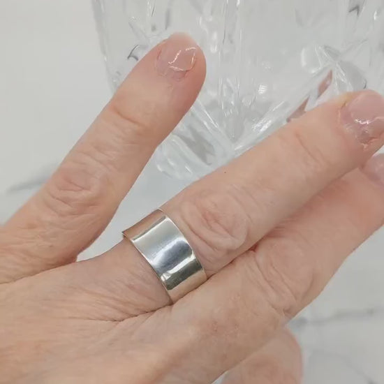 Video short of a model hand wearing the Argentium beveled ring  shown on white background with crystal glass.