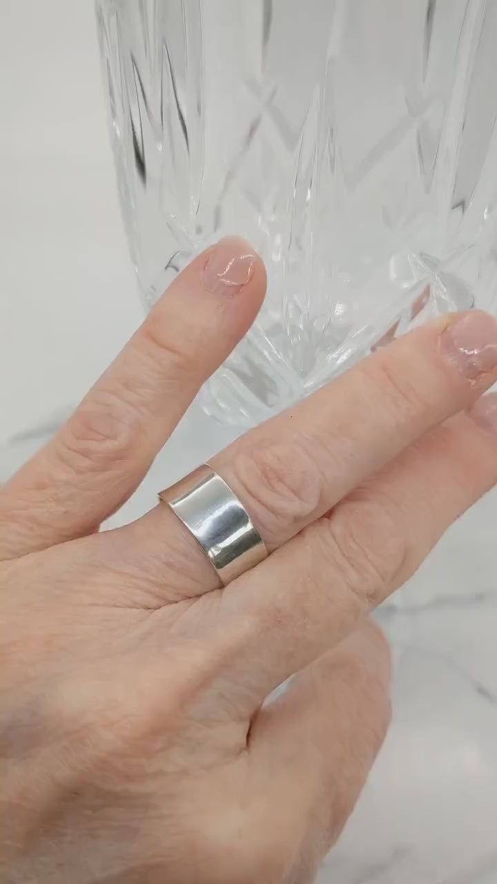 Video short of a model hand wearing the Argentium beveled ring  shown on white background with crystal glass.