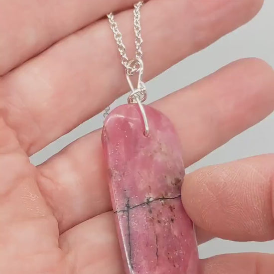 Demo clip showing both sides of the natural Rhodonite pendant in hand, with deep pink color and bold black veining.