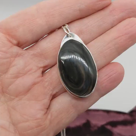 Demo clip of a  Mahogany Obsidian pendant displays swirling deep reddish-brown and dark mahogany hues, set in  Argentium® 935 Silver shown on white and burgundy background with silver necklace.
