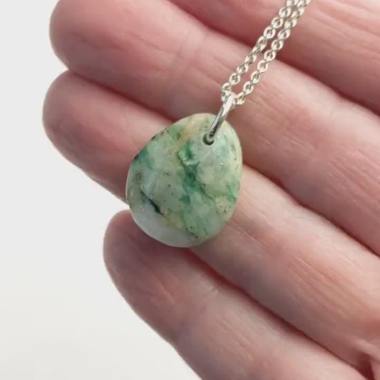 Demo clip of mariposite teardrop pendant shown in palm of hand against white background.