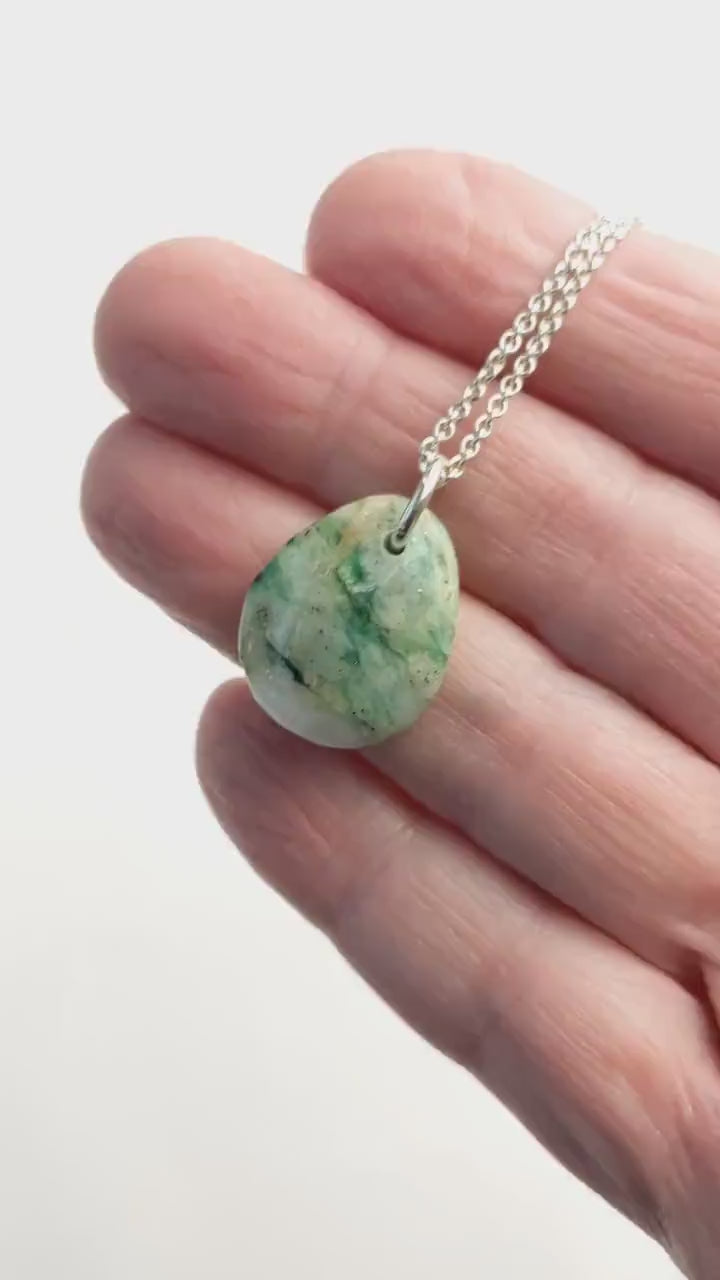 Demo clip of mariposite teardrop pendant shown in palm of hand against white background.