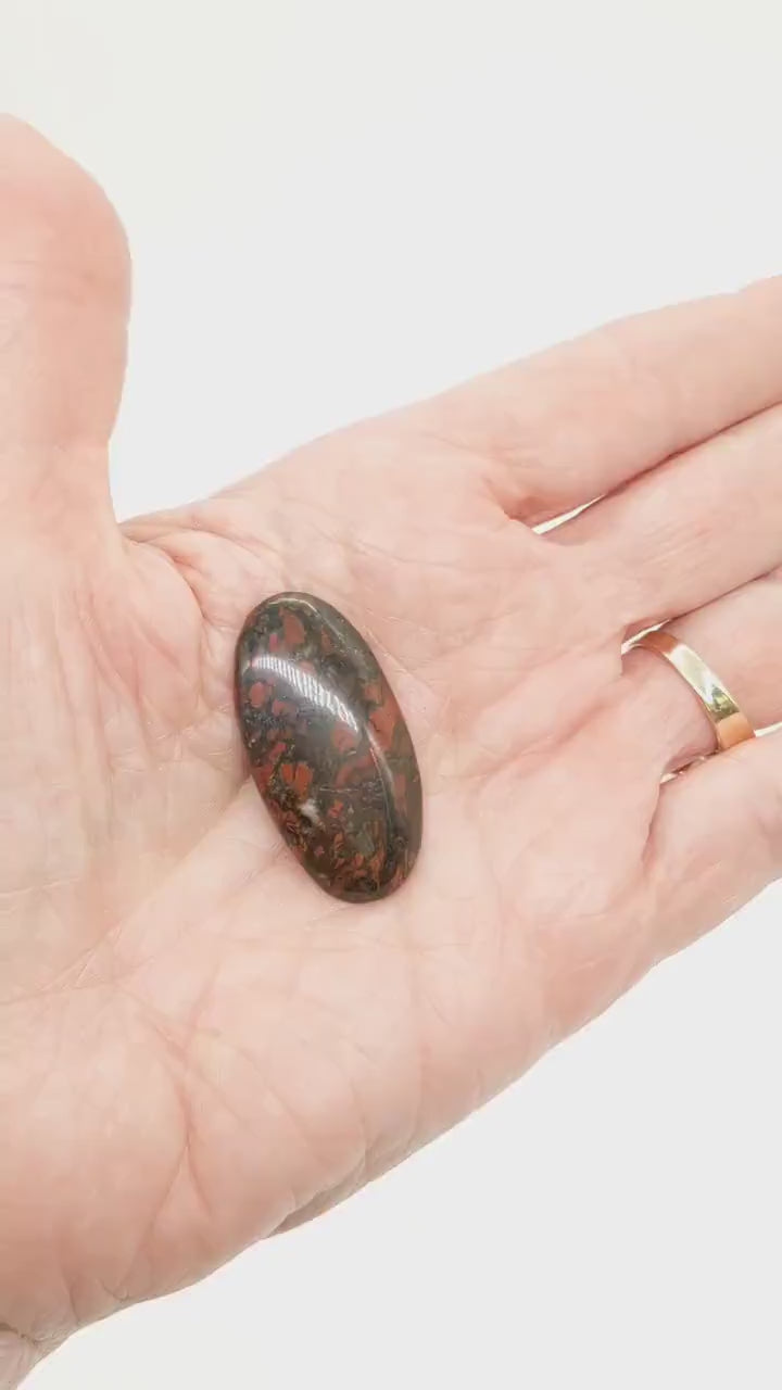 Demo clip of Red Jasper Cabochon shown in palm of hand on white background.