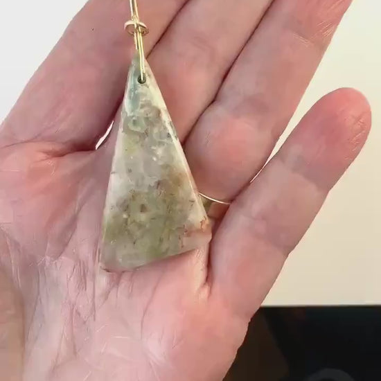 Demo clip of this natural Sunstone Pendant with a gold Filled custom bail.  Stone is shown in palm of hand against black and white background.