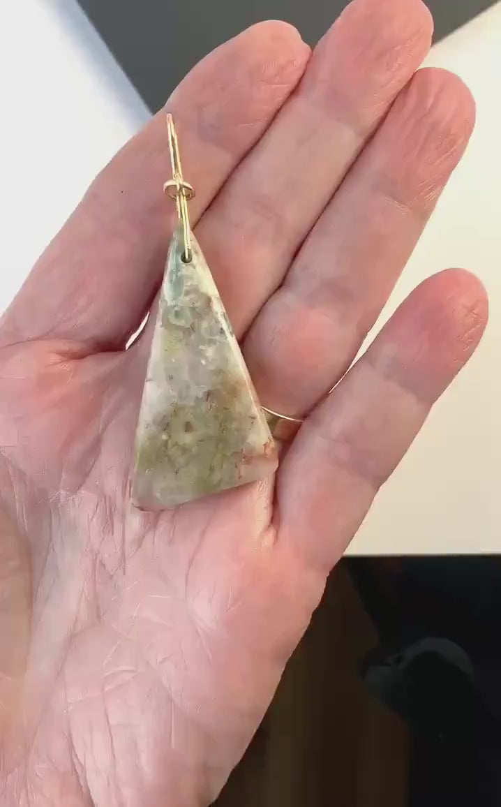 Demo clip of this natural Sunstone Pendant with a gold Filled custom bail.  Stone is shown in palm of hand against black and white background.