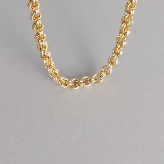 Hand showing the double cable link brass necklace to reveal its design.