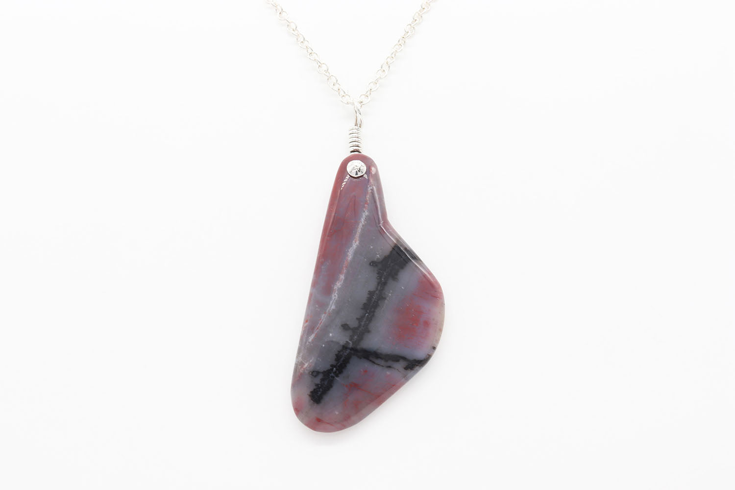 Petrified Rainbow Wood demo of features of this pendant against background of white glove and light gray background.