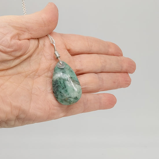 video of African Turquoise pendant shown in a hand displaying both sides with chain necklace.