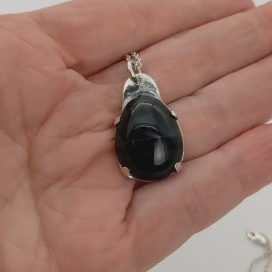 Demo clip in hand demonstration the features of this Blue Tiger's eye pendant necklace.