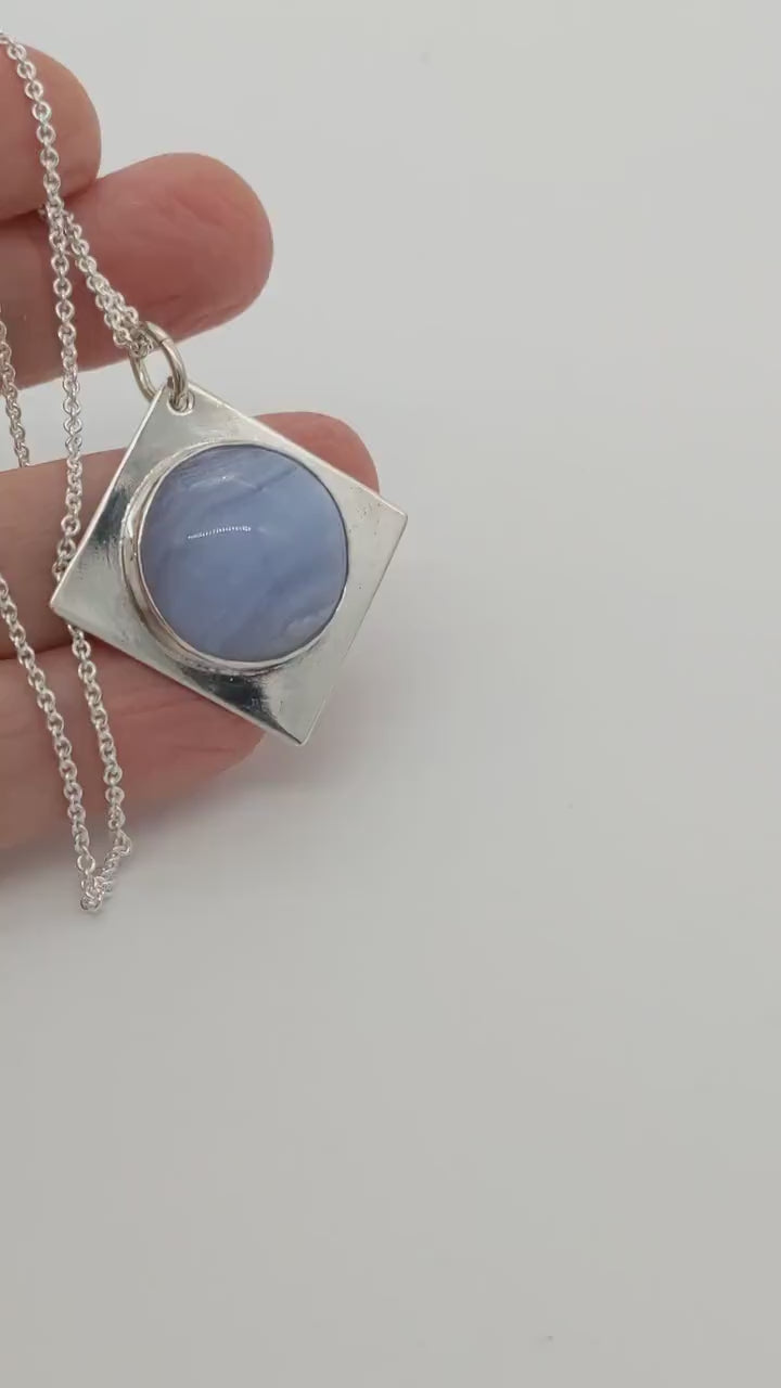 Blue Lace Agate Pendant in Argentium Silver shown in human hand demo of the features and shine of the pendant.