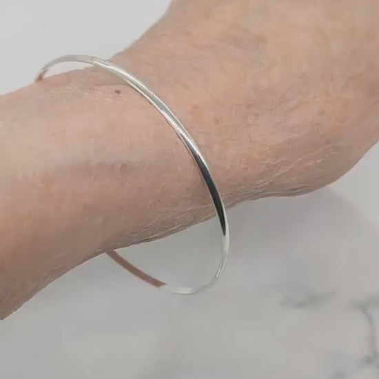 Video demonstration of Polished solid Argentium 935 silver half-round bangle bracelet handcrafted in Missouri on a human wrist that has a size of 6.25 inches.