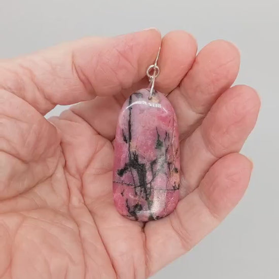Demo clip showing both sides of the natural Rhodonite pendant in hand, with deep pink color and bold black veining.