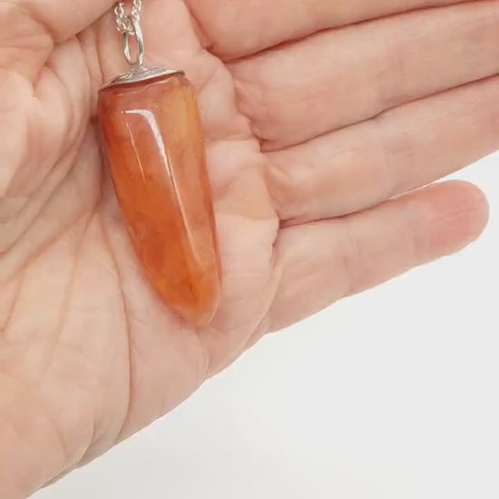 Demo clip of Natural Carnelian Crystal Pendant in palm of hand demonstrating the color and shine of this handcut pendant.