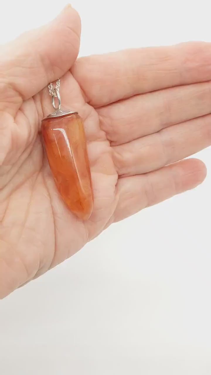 Demo clip of Natural Carnelian Crystal Pendant in palm of hand demonstrating the color and shine of this handcut pendant.