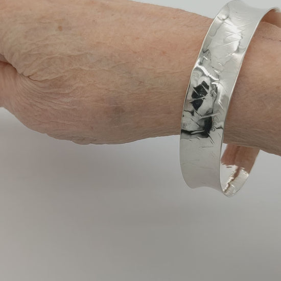 Demo clip of Argentium Anticlastic Bangle on human wrist shown on white background.