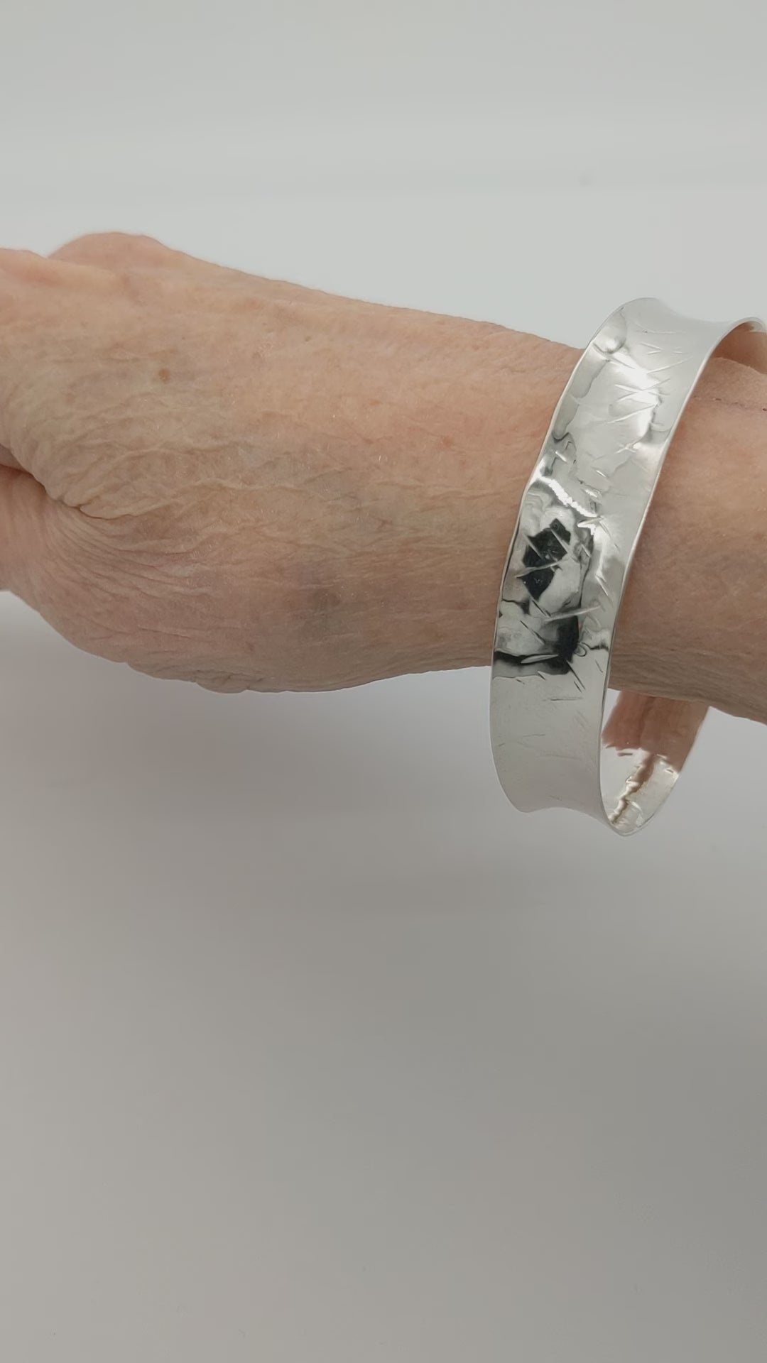 Demo clip of Argentium Anticlastic Bangle on human wrist shown on white background.