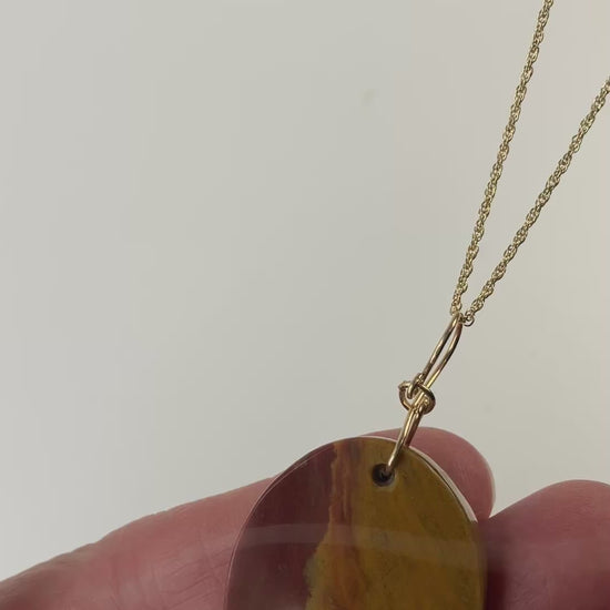 Demo clip of sonoran sunrise pendant in hand with gold fill chain as prop.