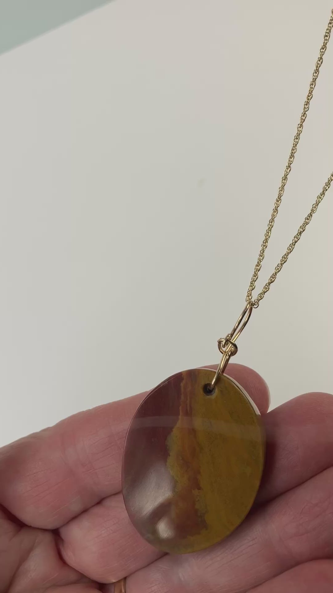 Demo clip of sonoran sunrise pendant in hand with gold fill chain as prop.