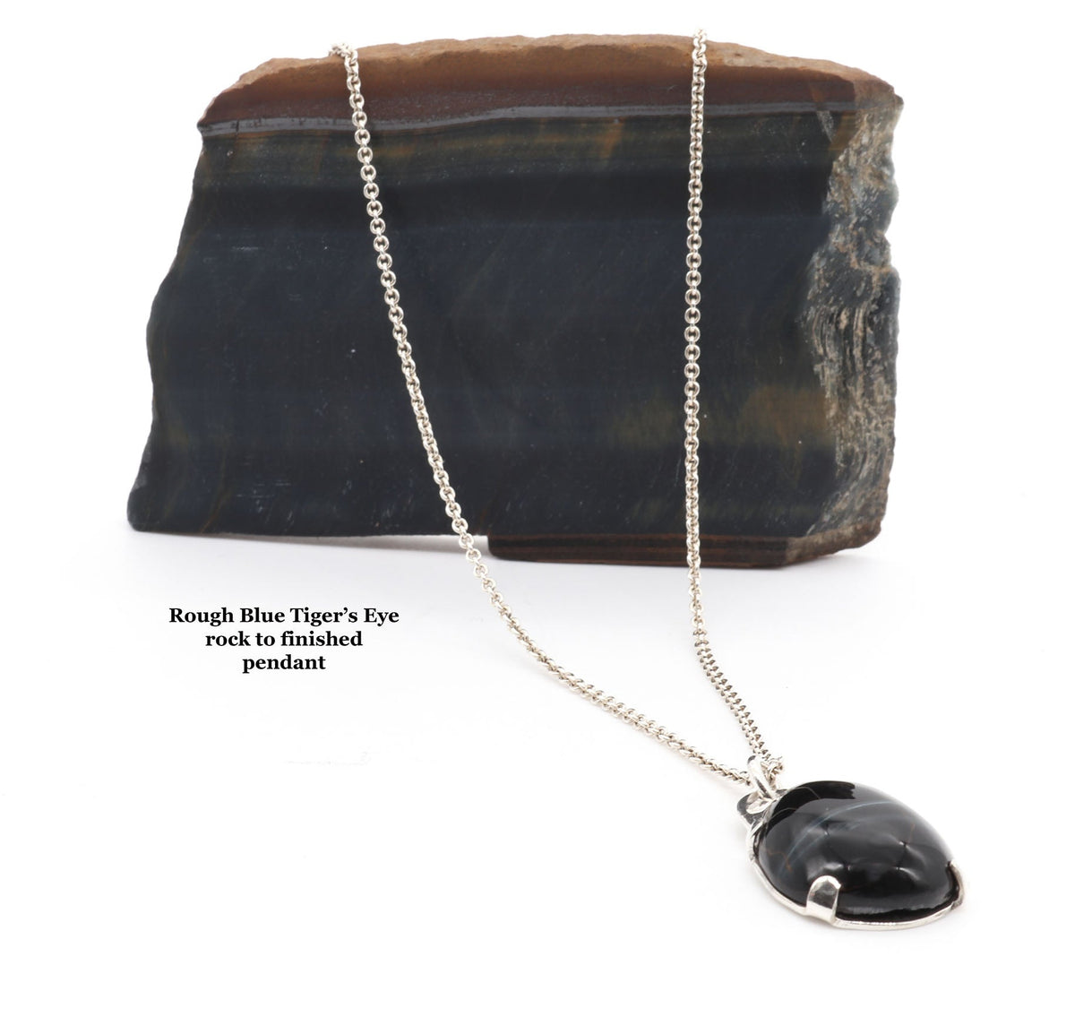 A silver chain necklace with a polished black pendant, displayed in front of a rough dark stone slab on a white background. Small text on the left reads 'Rough Blue Tiger's Eye neck to finished pendant'.