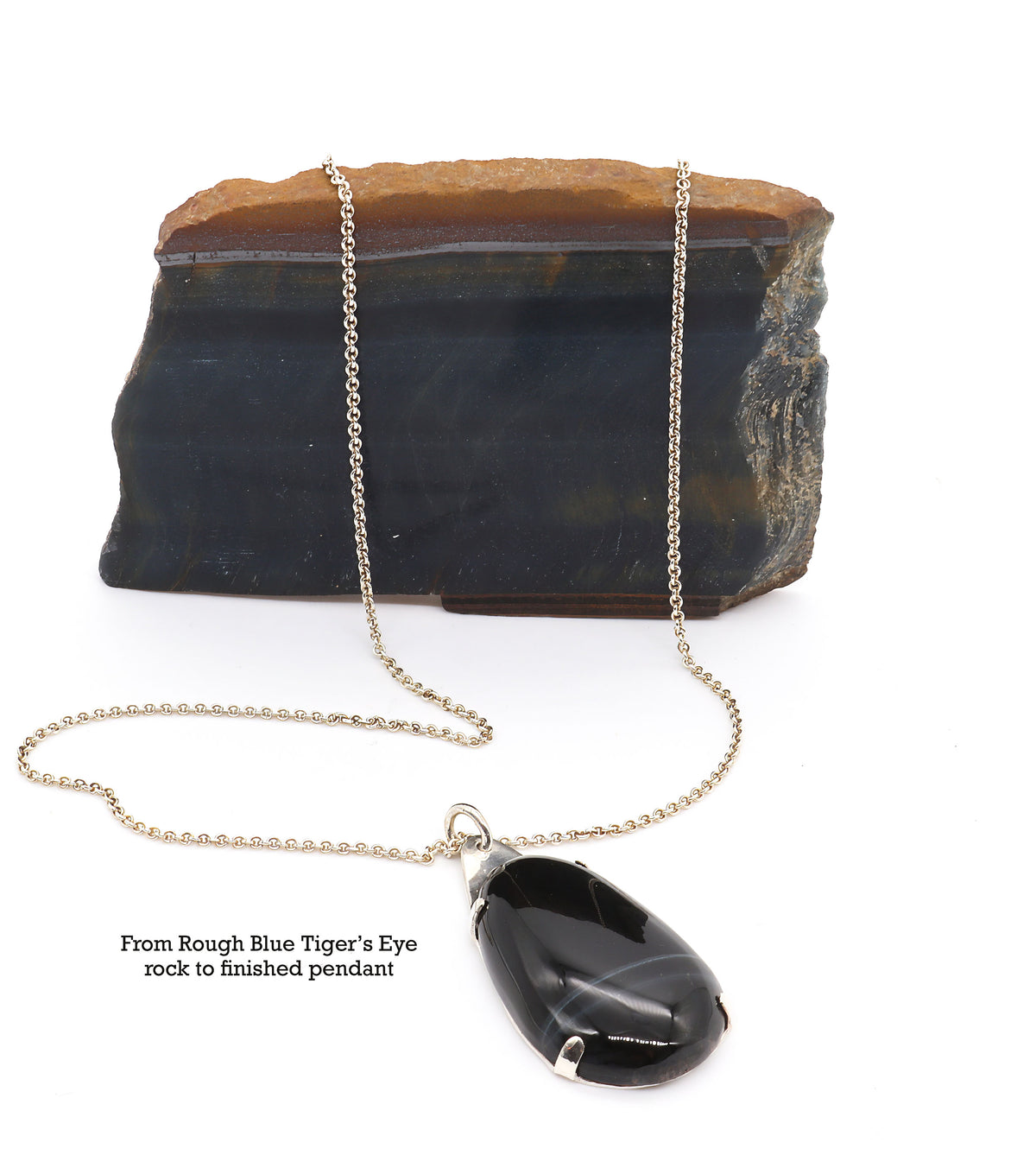 Handcrafted African Blue Tiger's Eye teardrop pendant with deep blue-black reflective gemstone, solid Argentium 935 silver tabbed setting and silver chain, displayed in front of a rough blue tiger's eye rock specimen. Text on the image reads 'From Rough Blue Tiger's Eye rock to finished pendant!'.