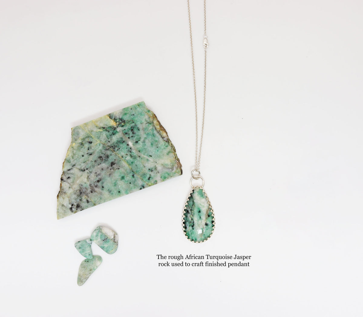 An African turquoise jasper pendant alongside a rough green jasper stone slab and two small jasper chips. A text label at the bottom right identifies the source stone. Text Overlay reads 'The rough African Turquoise Jasper rock used to craft finished pendant'