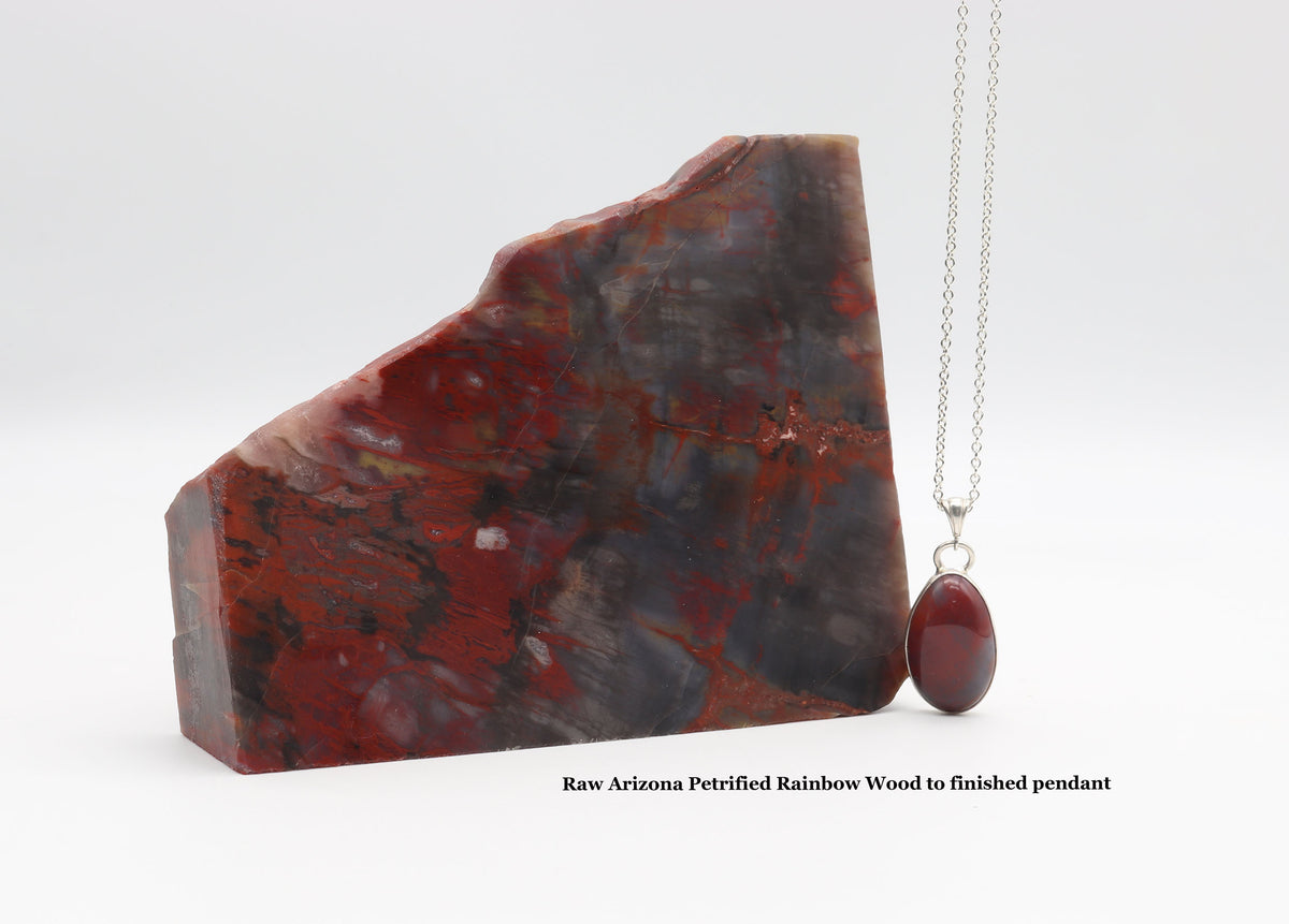 A rough red and black Arizona petrified rainbow wood rock shown next to a silver necklace with a Petrified Wood finished pendant on a white background. Text at the bottom reads 'Raw Arizona Petrified Rainbow Wood to finished pendant'.