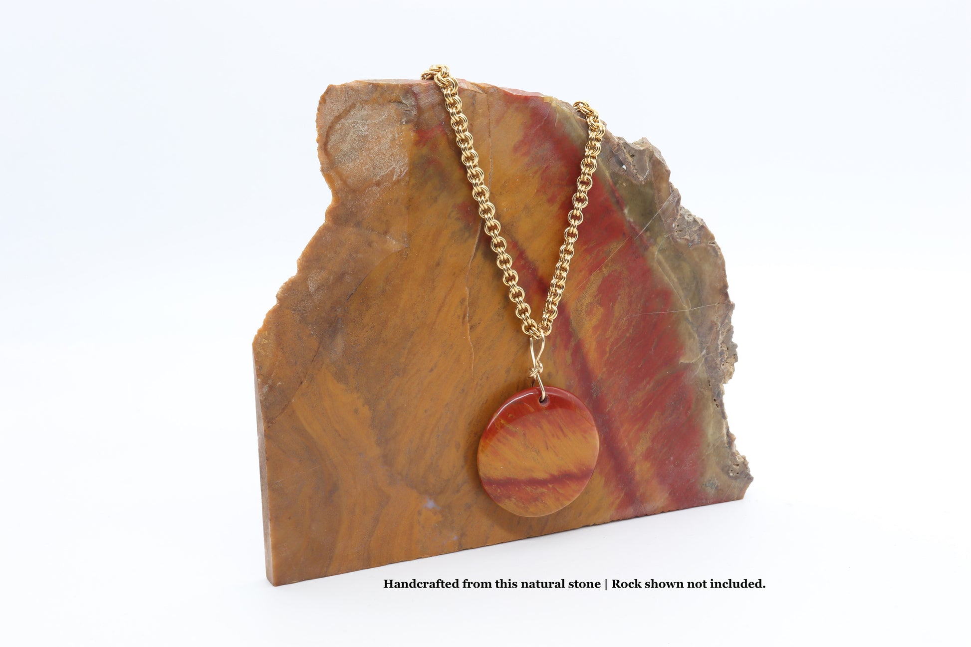 Red and orange Sonoran Sunrise cuprite pendant displayed on matching stone slab used for crafting this pendant.  Chain sold separately.