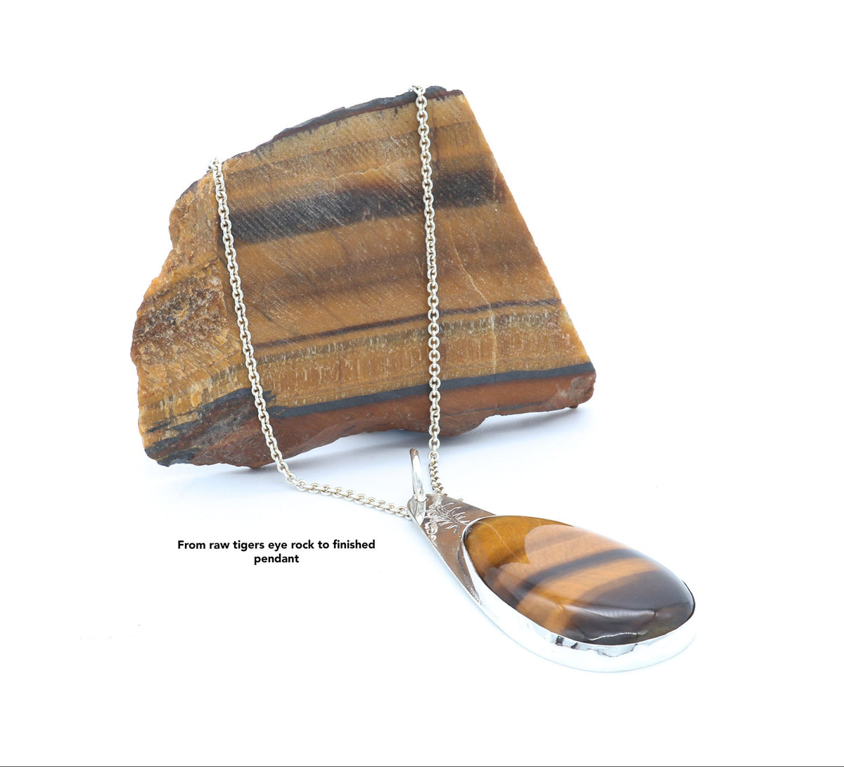 A silver tiger's eye pendant necklace  displayed next to piece of raw tiger's eye rock against a white background. Text overlay reads 'From raw tigers eye rock to finished pendant'