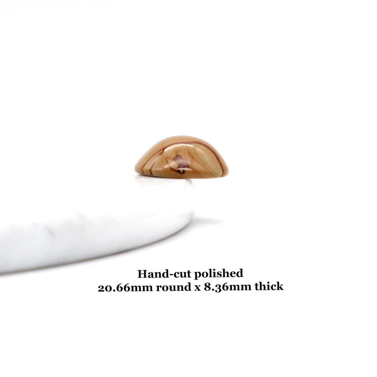 Side view of Round Picture Jasper cabochon with natural tan and brown landscape-like banding shown resting on a white marble slab on white background. Text overlay reads 'Hand-cut polished
20.66mm round x 8.36mm thick'