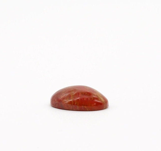 Side View of Sonoran Sunrise Chrysocolla Cuprite gemstone,  handcut and polished into an oval shape cabochon, revealing its natural vibrant shades of warm reds and yellow, reminiscent of a desert sunrise.   Shown on white background.