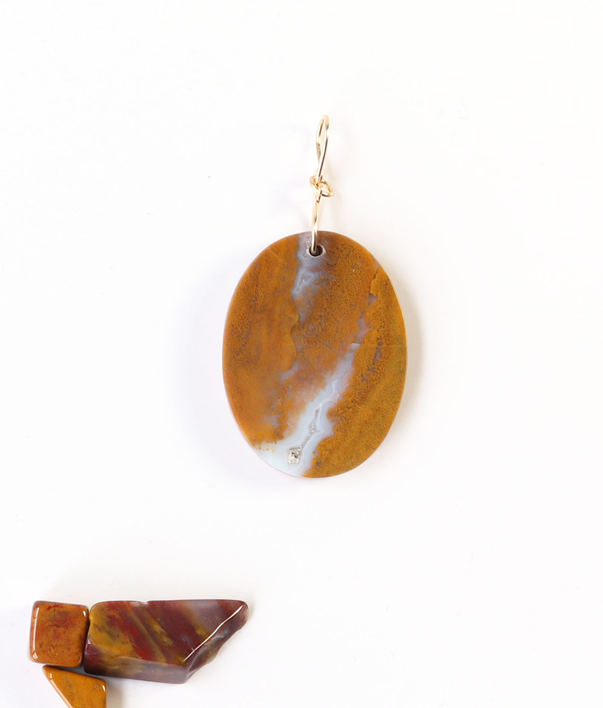 One-of-a-Kind Sonoran Sunrise Pendant – Hand-Cut in Missouri with warm golden ochre tones with soft white veining and natural crystal inclusions. Shown on white background with pebbles of polished sonoran sunrise shown for props.