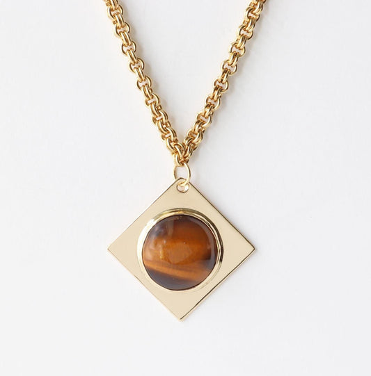A closeup of a 1.625 Tiger’s Eye pendant, featuring a .75” round cabochon set in a four-point diamond-shaped NuGold brass setting. This one-of-a-kind artisan pendant is hand-cut and polished in our Missouri studio, ensuring a high-quality, handcrafted component for your custom jewelry designs.  Shown against white background with double-link brass chain sold separately.