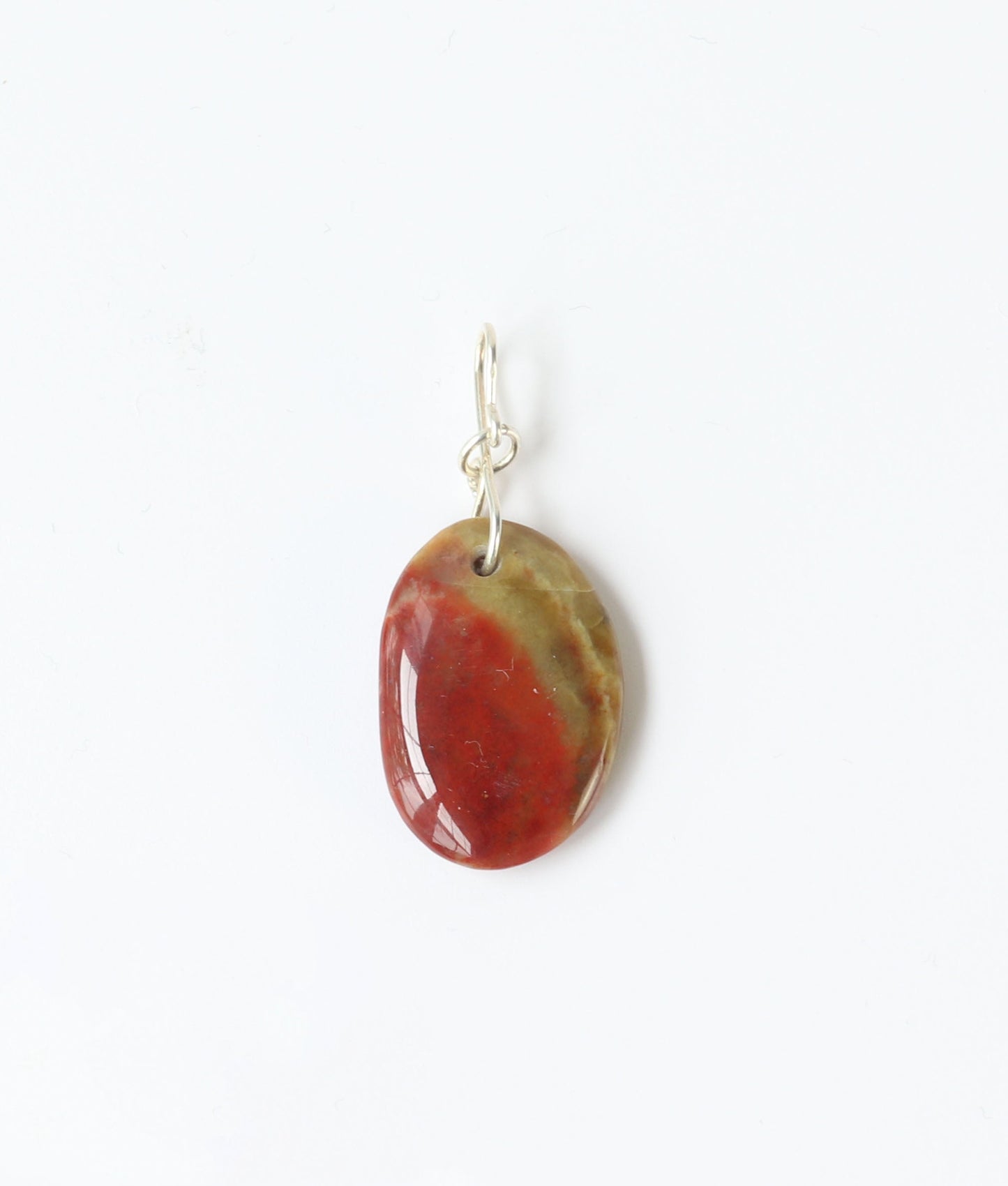 Oval-shaped sonoran sunrise pendant with a red and green color pattern on a white background